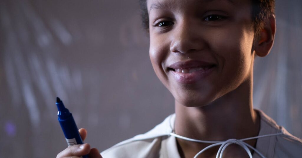 A cheerful boy holding a marker, captured indoors with a soft focus background.