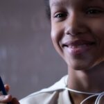 A cheerful boy holding a marker, captured indoors with a soft focus background.