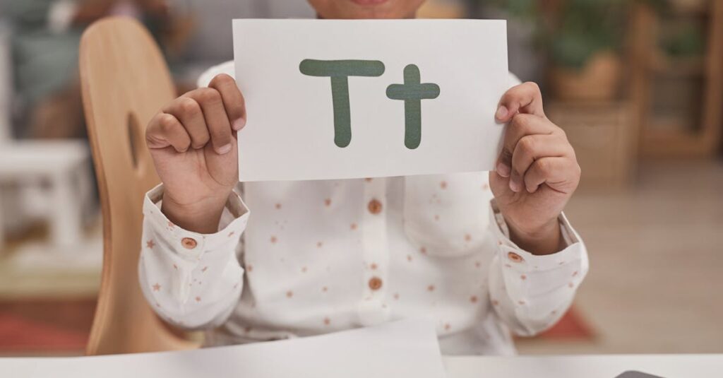 Close-up of child holding card with letter T in classroom, encouraging early education.