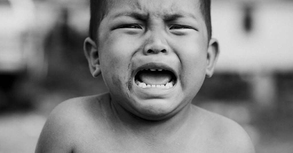 Heartfelt portrait of a young child crying, showcasing raw emotion in black and white.