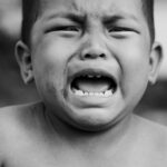 Heartfelt portrait of a young child crying, showcasing raw emotion in black and white.