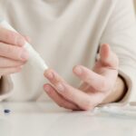 Close-up of a person using a glucometer to test blood sugar at home.