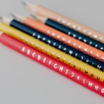 Colorful alphabet pencils neatly arranged on a gray background, ideal for educational themes.