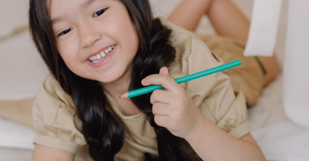 Happy child lying indoors with a pencil and music sheets, embracing creativity and learning.