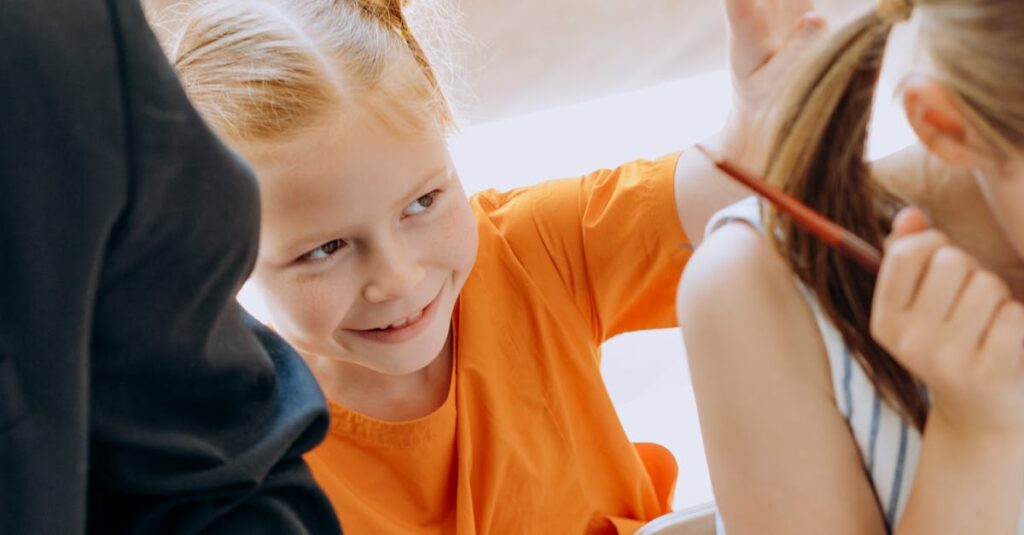 Two young girls having fun while sitting at a classroom table, engaged in playful learning activities.