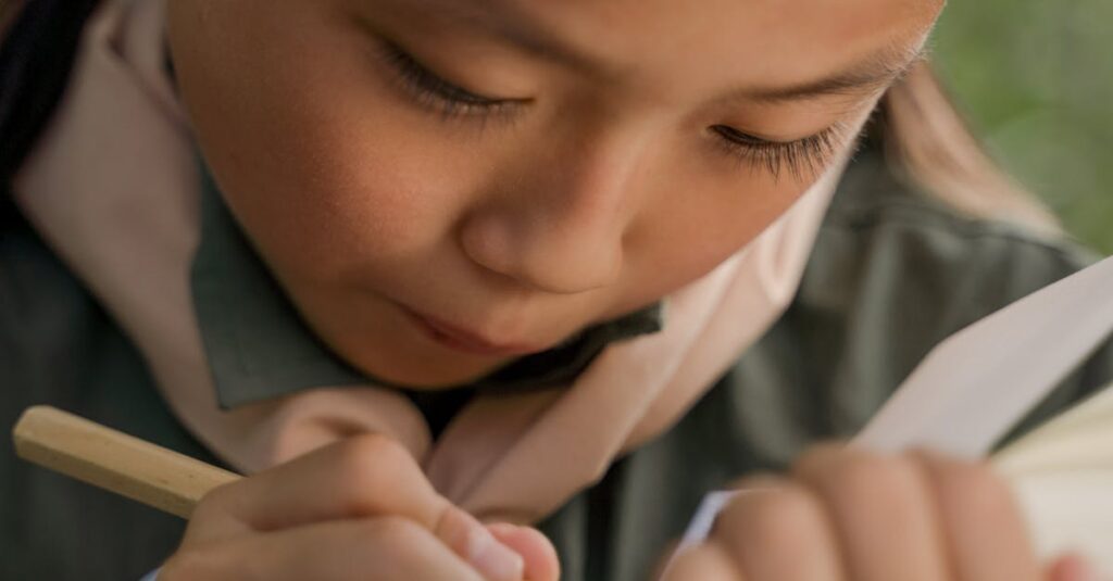 A young girl scout concentrates on writing in her notebook during an outdoor activity.