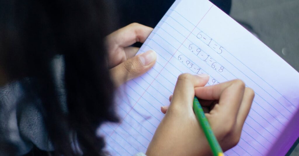 From above of crop anonymous diligent clever girl solving homework and writing in notepad
