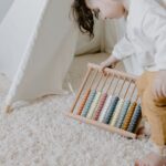 A toddler engaged with an abacus while in a cozy indoor playroom.